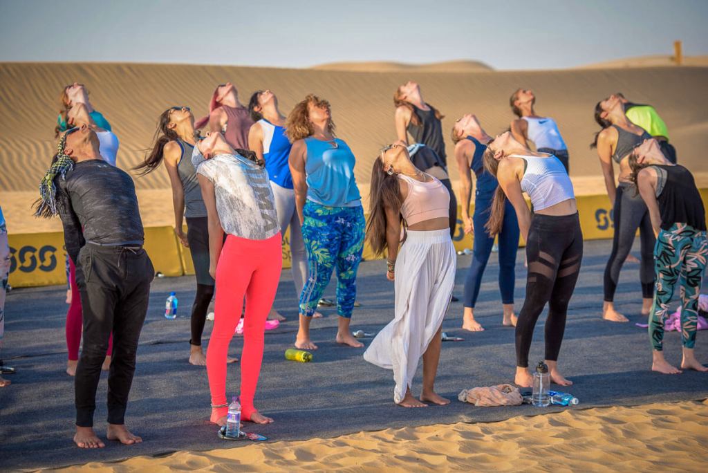 A group of people doing yoga on a desert