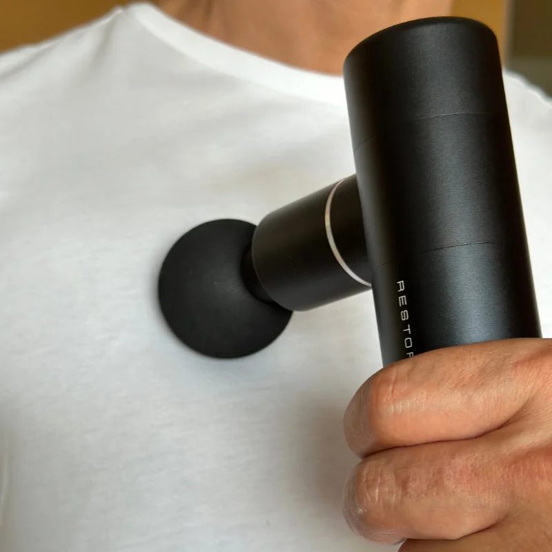 A man relaxing their chest muscles with a massage gun